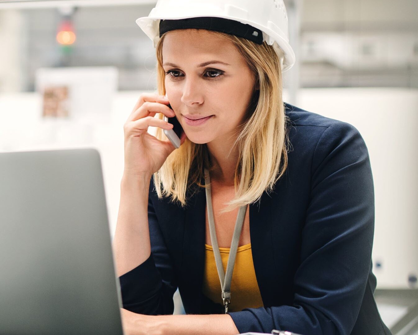 A female employee on the phone wearing a health & safety helmet