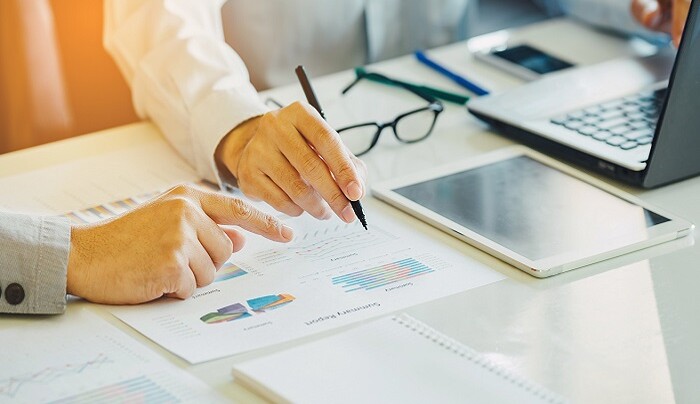 Two businessman analysing company financial report balance sheet statement working with documents graphs.