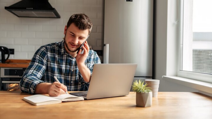 A happy male employee working from home on the phone