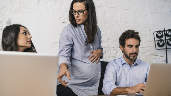 Creative people doing a brainstorming meeting in a modern studio with one of the employees being pregnant