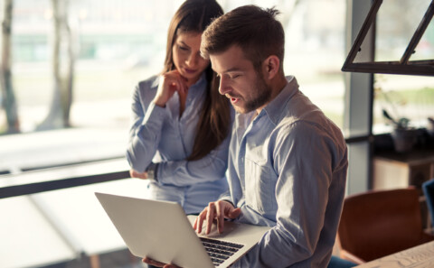 I Need a Health and Safety Plan – Where do I Start? Hero image is of a caucasian man and woman talking whilst the man holds a laptop. They are both in office wear.