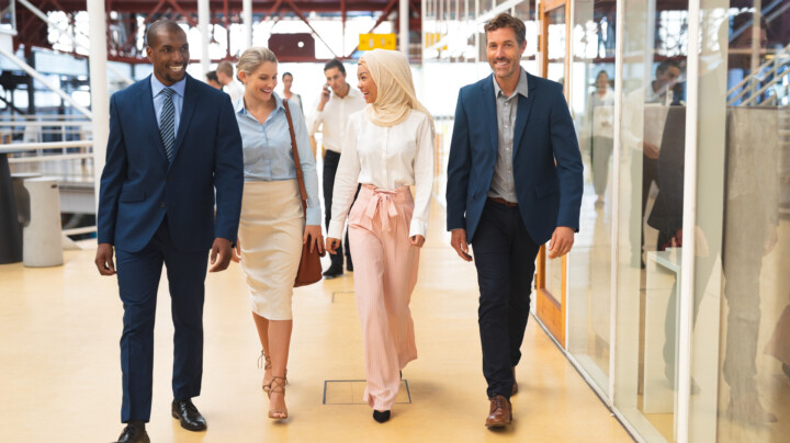 Employees wearing different business outfits and walking down a corridor