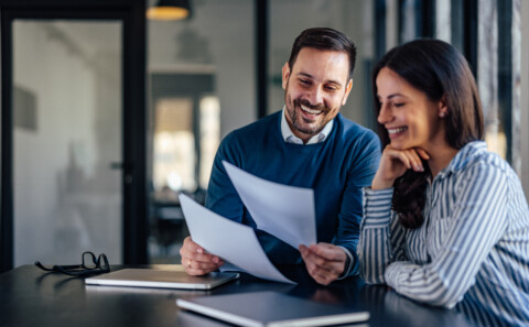 Happy male employee showing some documents to his female colleague