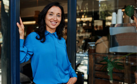 Happy cafe owner posing when standing in front of the cafe