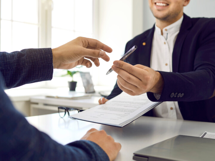 Employee hands over contract and a pen to another employee